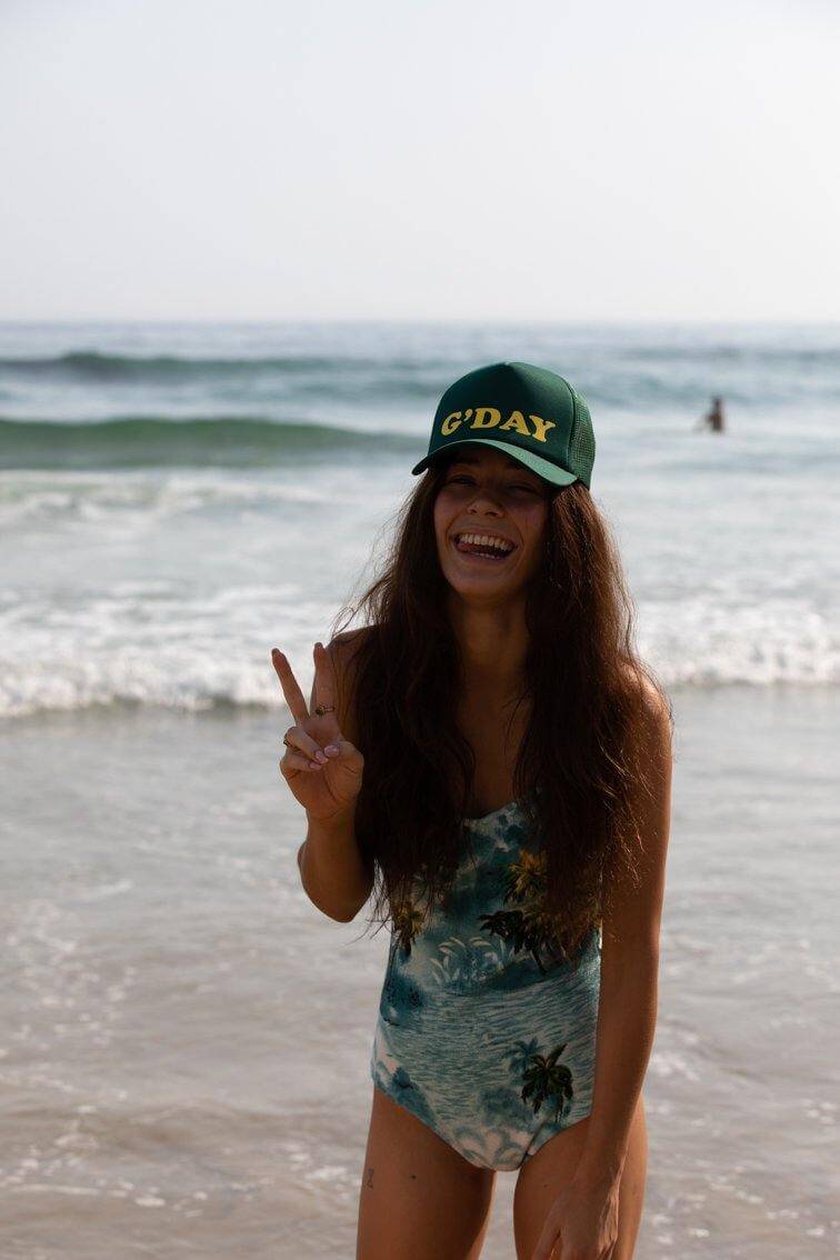 Happy Australian girl wearing G'Day high crown trucker cap with mesh back and snapback at the beach - Tropic Trucker Australia®